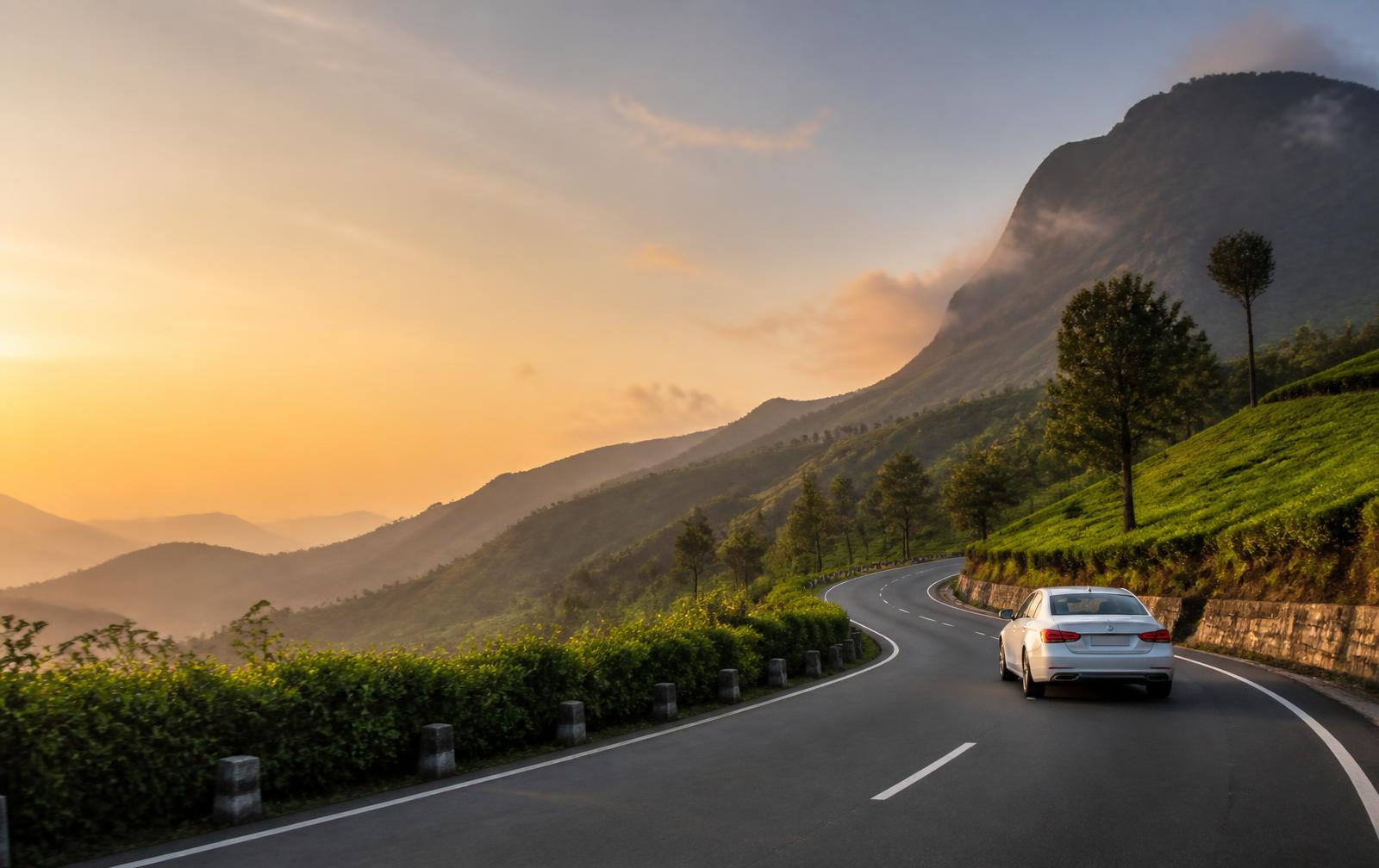 A car travelling on a scenic mountain road at sunrise